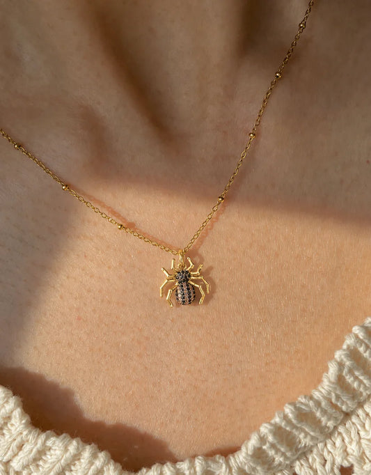 Model wearing an 18k gold finish spider pendant with zircon diamonds on a classic link chain.