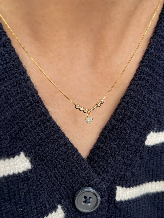 Model wearing personalized Morse code initials necklace with tiny heart stone in 22 karat gold jewelry minimalist everyday necklace