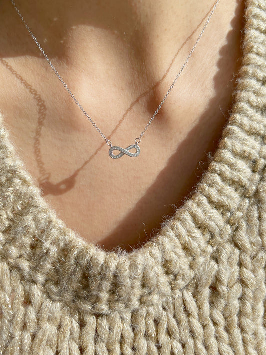 Close-up of silver infinity pendant necklaces on neck