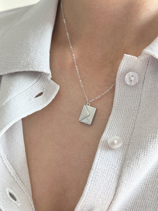 Model wearing silver polished envelope pendant with hidden love message