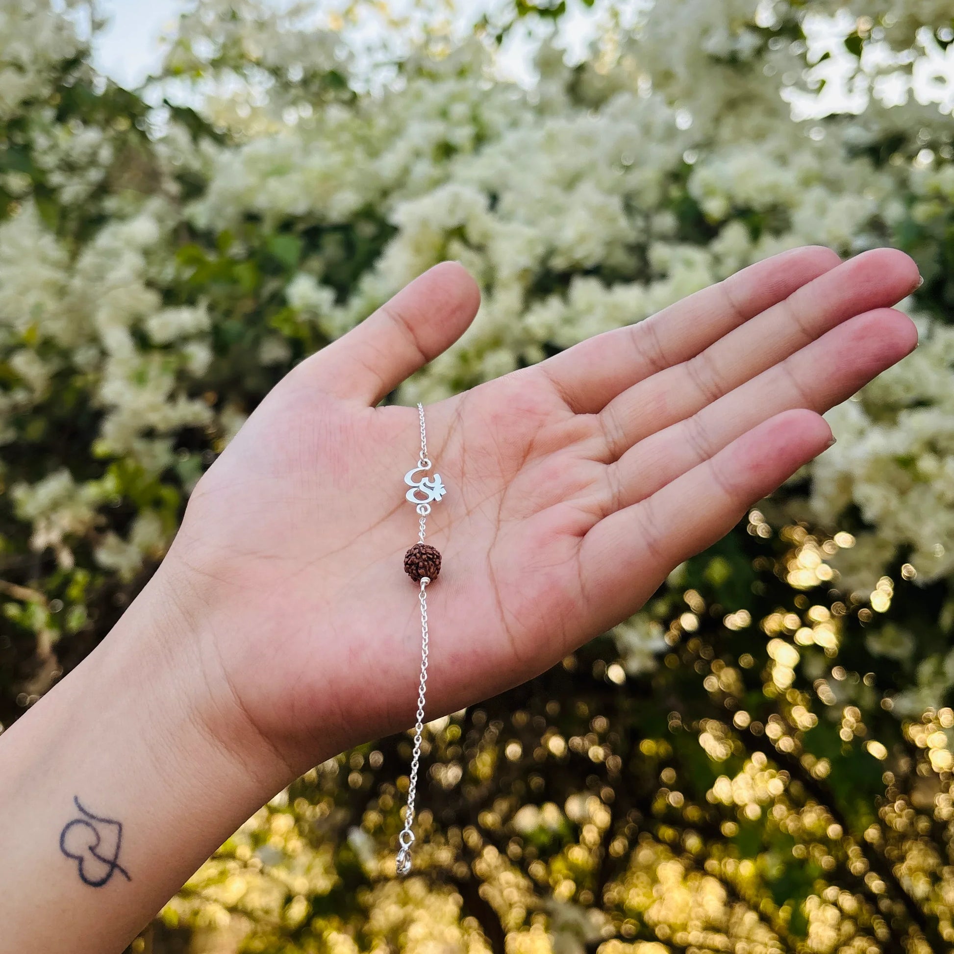 Pure silver Om Rudraksha bracelet held in hand with natural background – spiritual jewelry for men and women