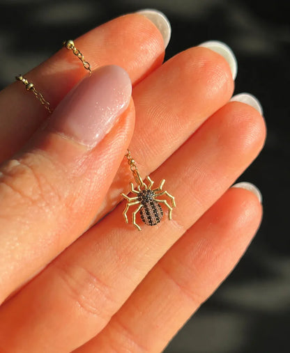 Hand holding a 9mm spider charm to show the scale and detail of the zircon diamond setting.