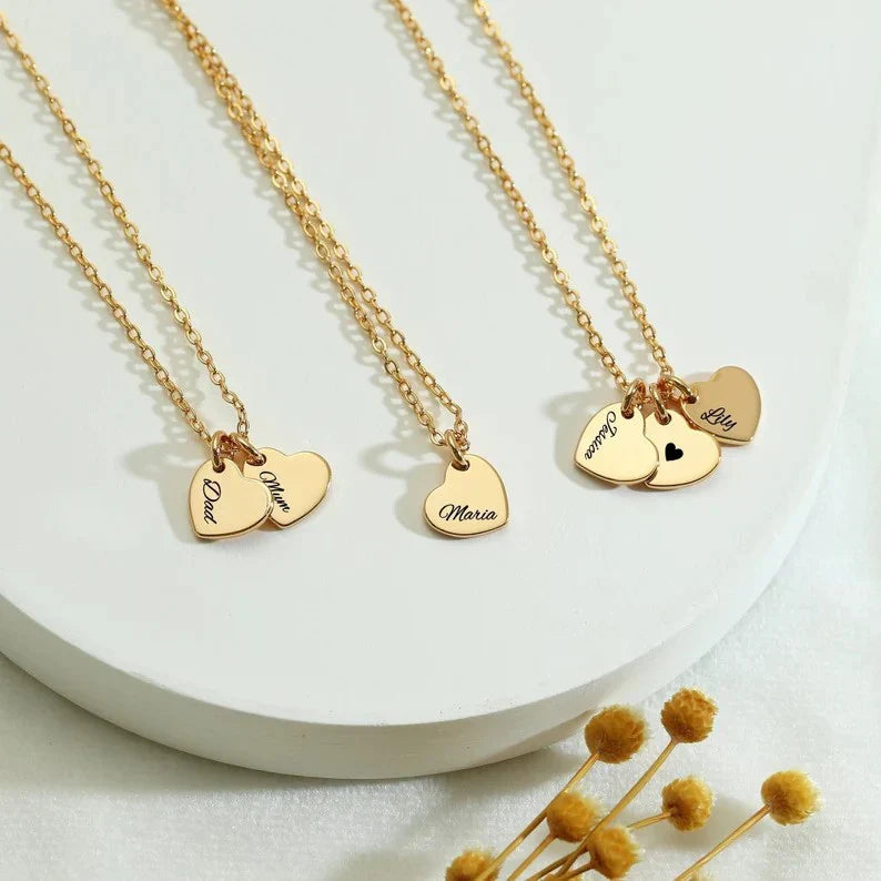Eraya Jewel Custom Heart with Family Name pendants in a trio, possibly showing gold plated, silver plated, and different family name engravings to highlight customization options
