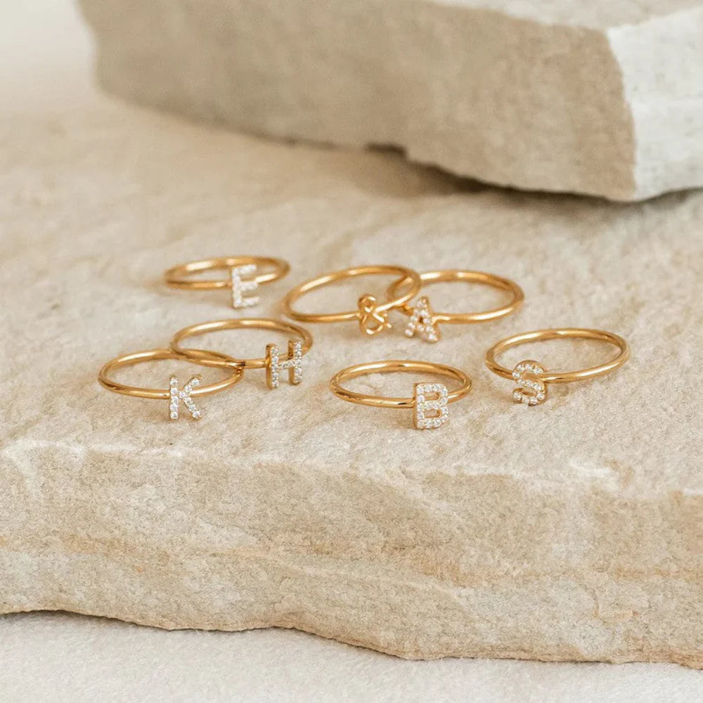 isplaying a trendy ring stack featuring the Custom Pavé Diamond Initial Ring.