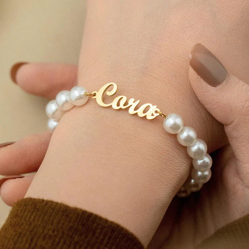 Close-up on wrist showing the custom engraved nameplate on the Eraya Jewel pearl bracelet.