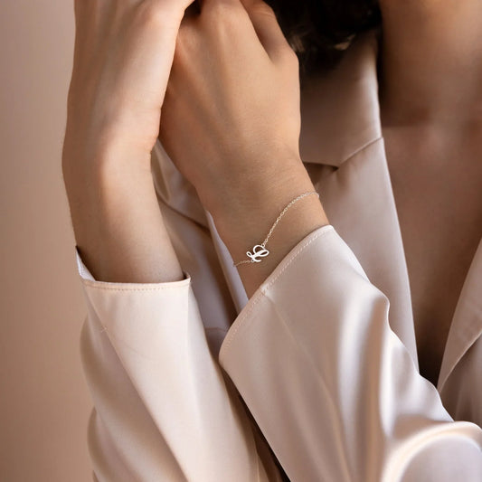 Model's wrist adorned with an Eraya Jewel 'Carrie Font' Initial Bracelet in Silver, showcasing the elegant script initial.
