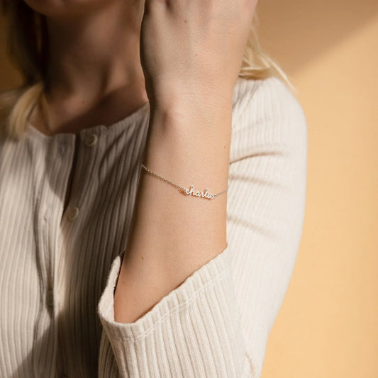 Young girl happily wearing her Eraya Jewel Custom Delicate Name Bracelet in Gold, showcasing a personalized nameplate on her wrist.