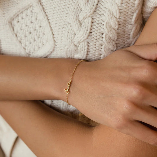Model elegantly wearing an Eraya Jewel Dainty Name Bracelet in Gold, showcasing its delicate personalized style on her wrist