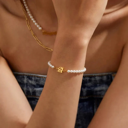 Model wearing the personalized Eraya Jewel 'Your Initial Letter Pearl Bracelet' in gold Polish.
