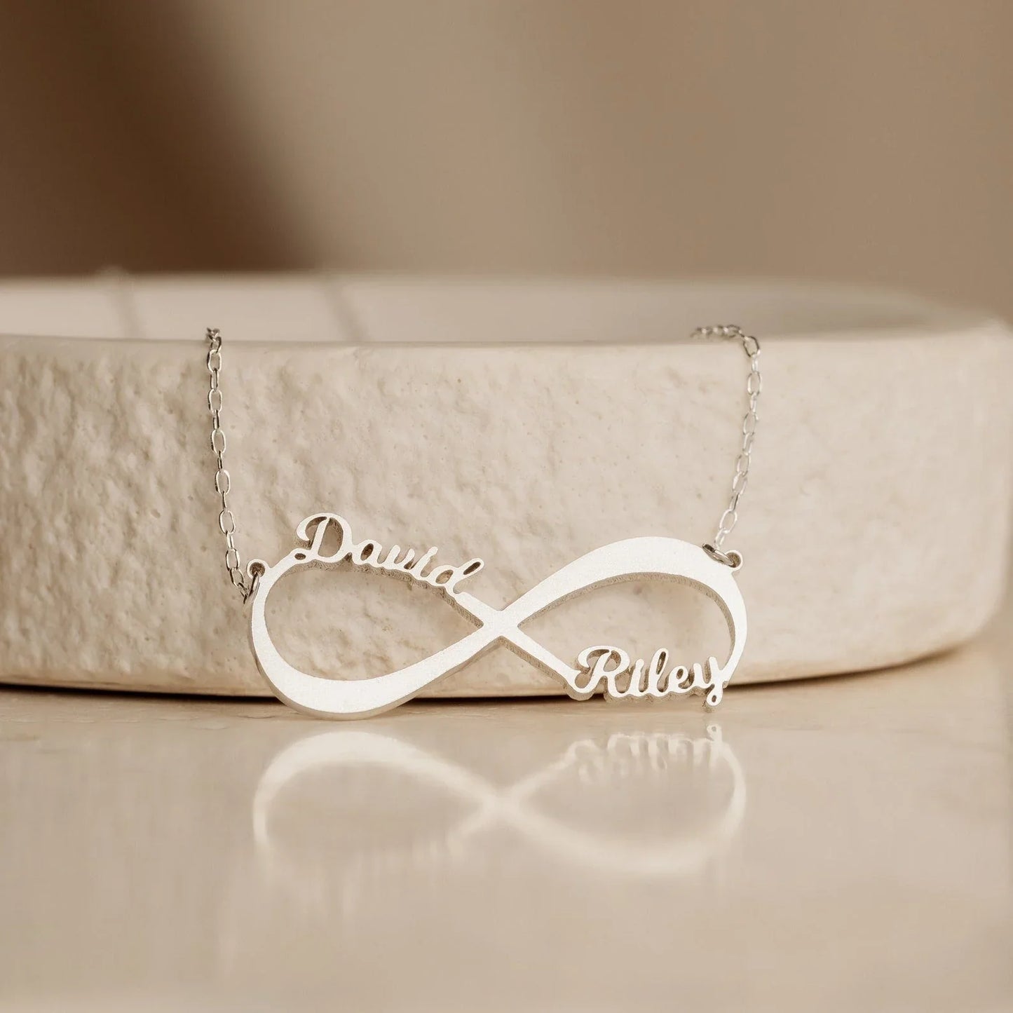 Close-up of the Personalized Name Infinity Necklace in gold, showcasing custom engraved names on a sleek infinity symbol