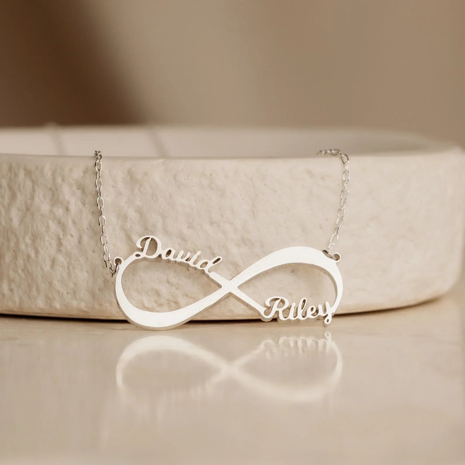 Close-up of the Personalized Name Infinity Necklace in gold, showcasing custom engraved names on a sleek infinity symbol
