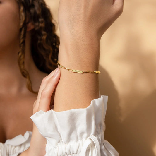 Model elegantly wearing an Eraya Jewel Engraved Mini Name Bar Bracelet in Gold, showcasing its delicate personalized style on her wrist.