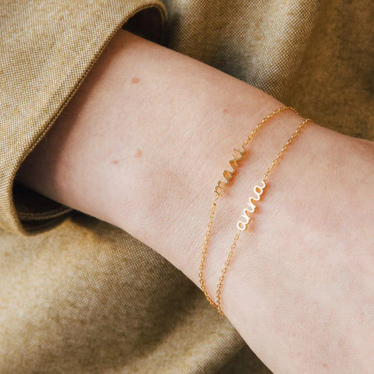 Model showcasing an Eraya Jewel Dainty Layering Name Bracelet in Gold, perfect for a subtle personalized statement on the wrist.
