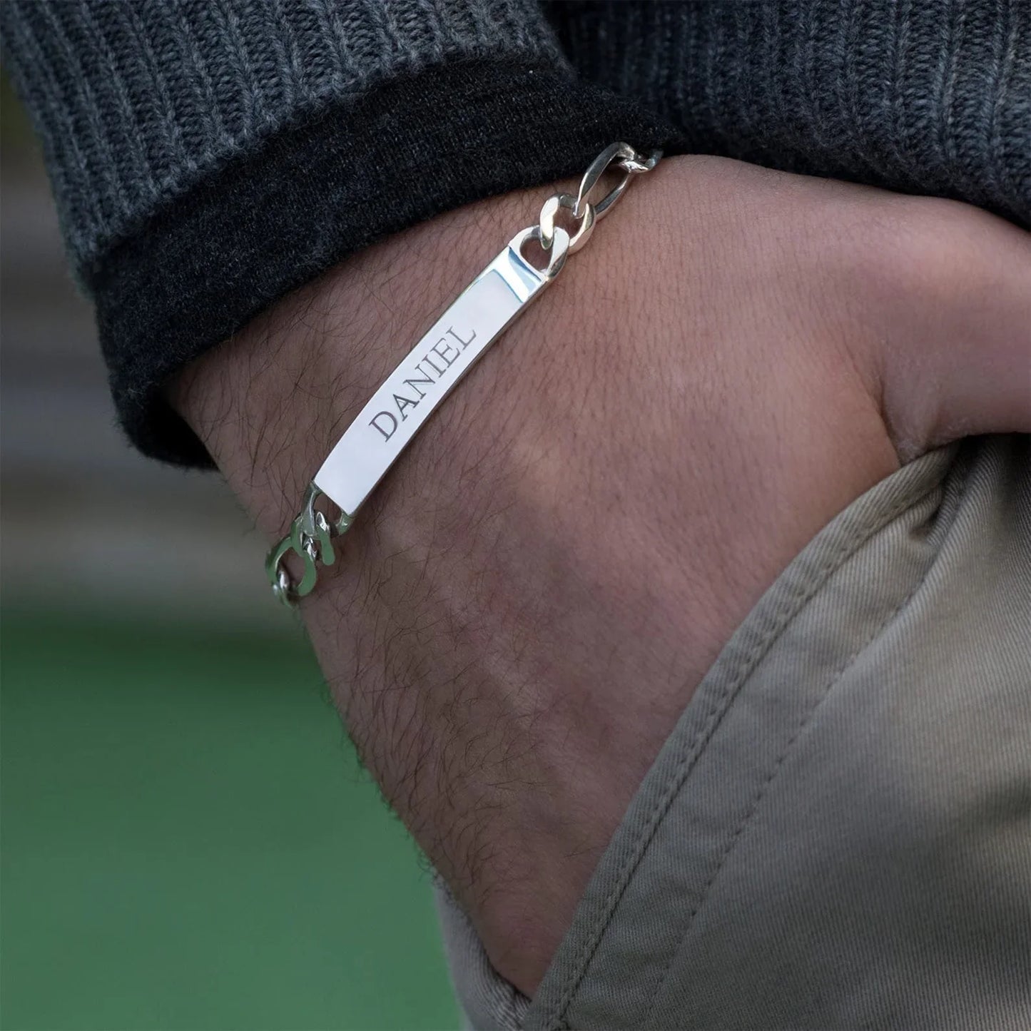 Close-up of a model wearing the Eraya Jewel Custom Engraved Men's ID Bracelet in Silver, focusing on the detailed personalization.