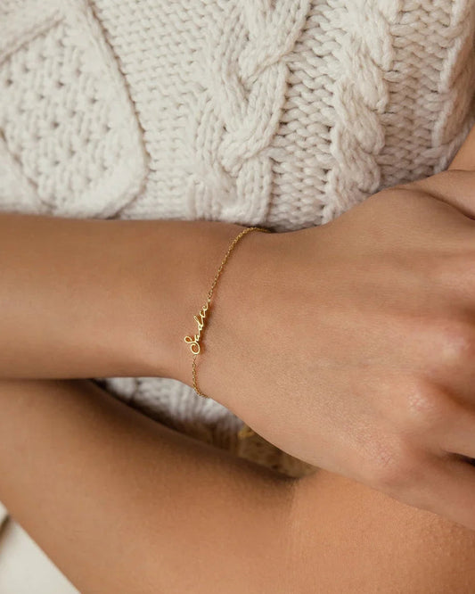Model elegantly wearing an Eraya Jewel Dainty Name Bracelet in Gold, showcasing its delicate personalized style on her wrist