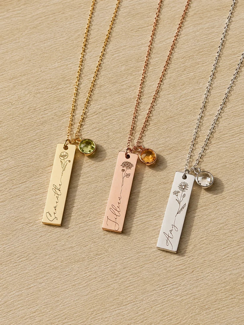 Three Eraya Jewel personalized birth flower, name, and birthstone pendants displayed in gold, rose gold, and silver finishes, showcasing custom botanical engravings and vibrant 6mm gem charms.