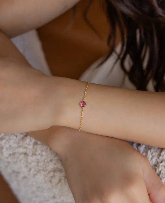 Eraya Jewel dainty birthstone bracelet worn on a woman's wrist with a pink birthstone