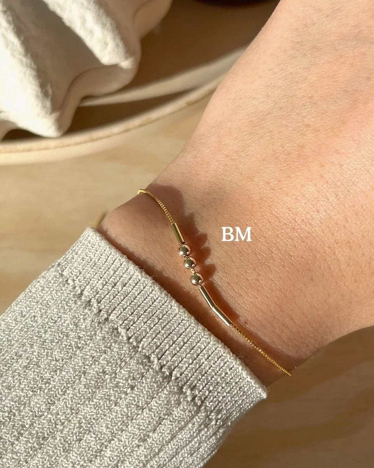 Eraya Jewel personalized gold Morse code bracelet worn on a wrist with BM encoded in dots and dashes