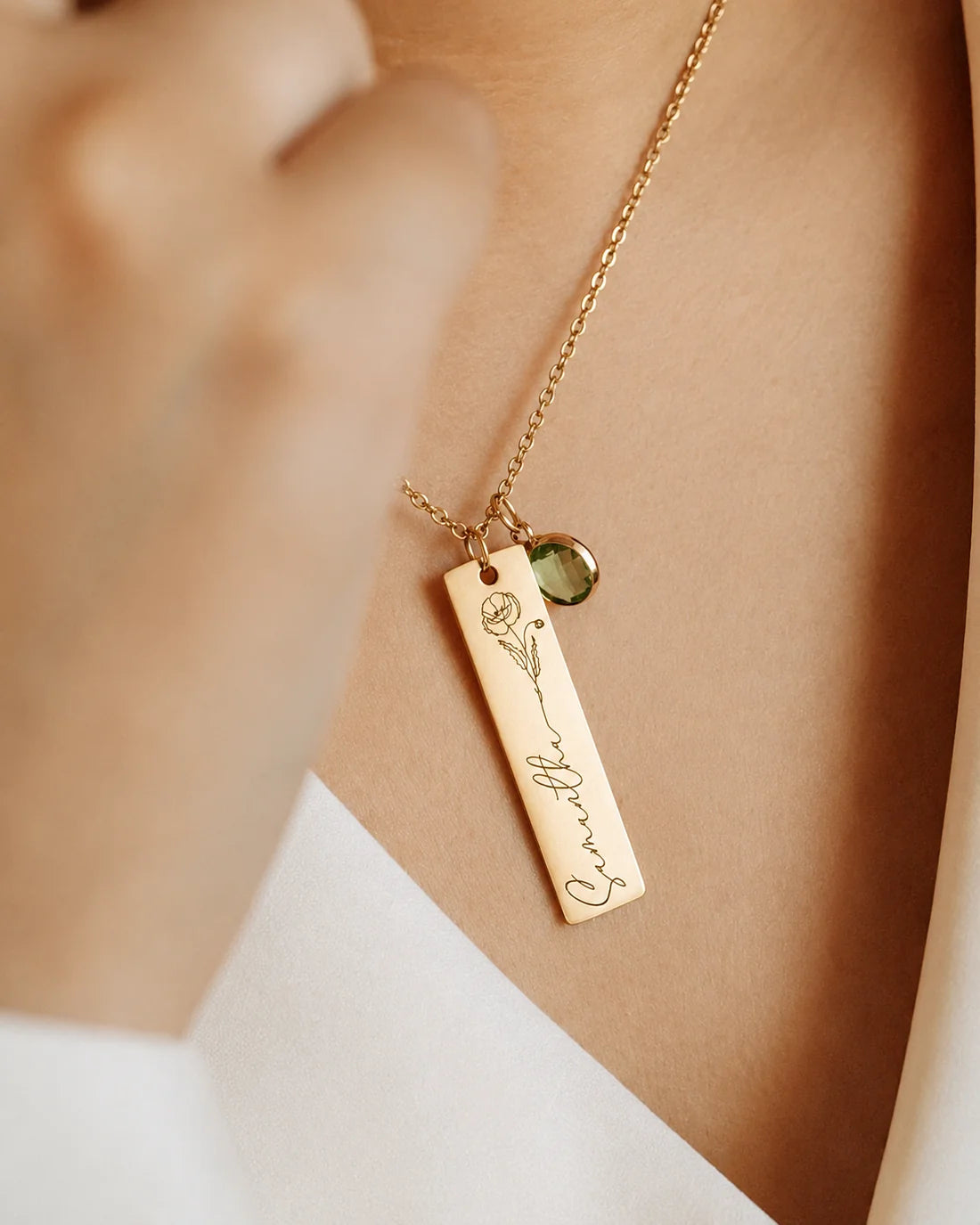 Model wearing an Eraya Jewel gold personalized birth flower, name, and birthstone pendant, featuring the custom engraved name Samantha, an August poppy flower, and a 6mm green peridot gem charm.