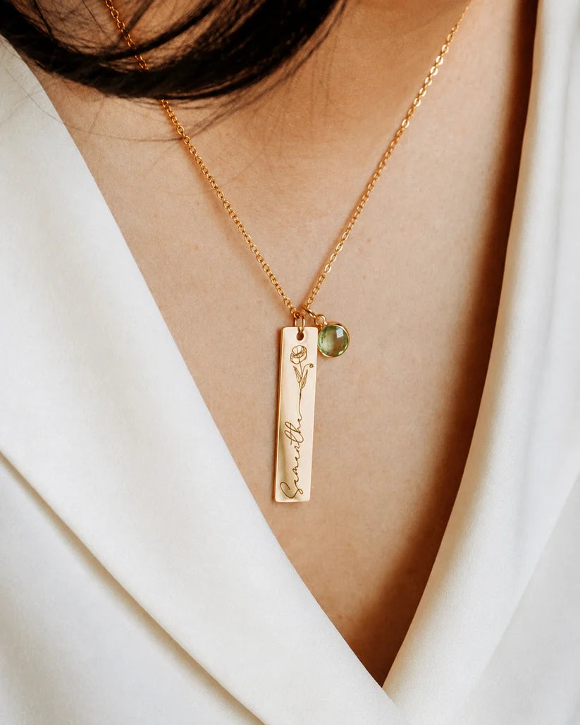 Close-up detailing the custom engraving on an Eraya Jewel gold personalized birth flower, name, and birthstone pendant, highlighting the floral artwork and green peridot charm.