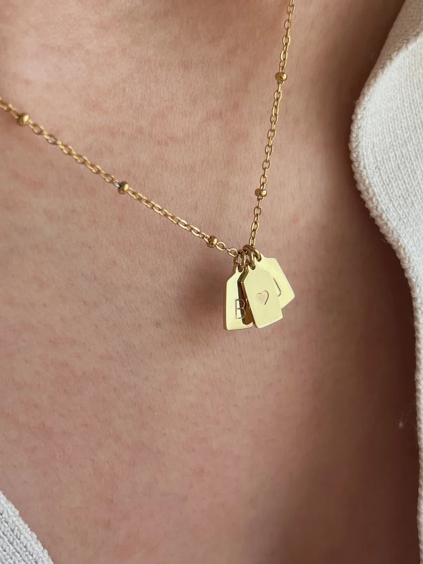 Close-up of Eraya Jewel personalized heart initial pendant with engraved initials on delicate tag charms
