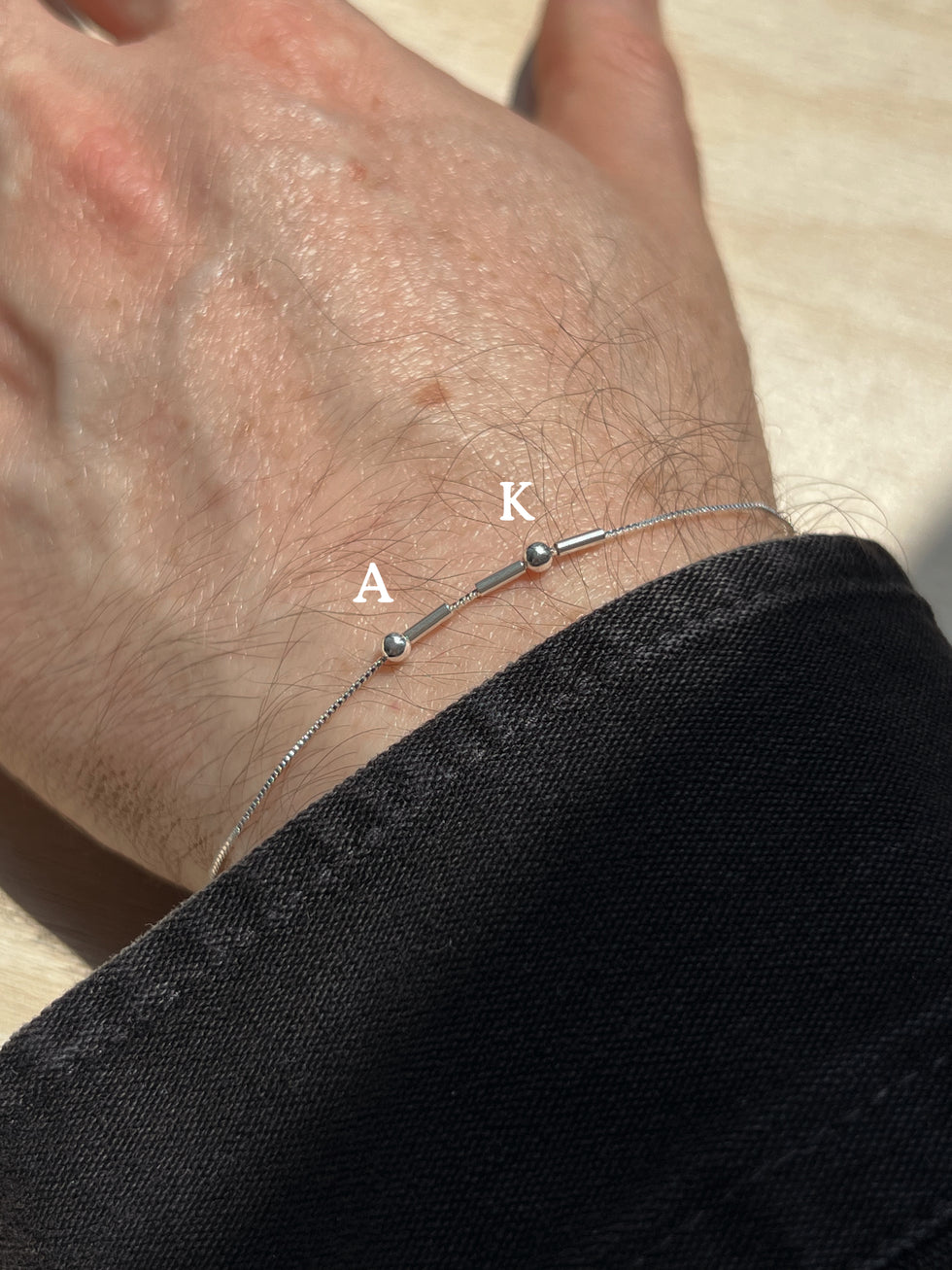 Eraya Jewel silver Morse code bracelet worn on a wrist with A and K initials represented in Morse code