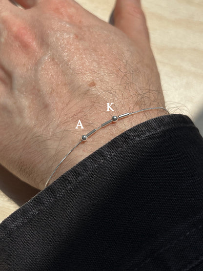 Eraya Jewel silver Morse code bracelet worn on a wrist with A and K initials represented in Morse code
