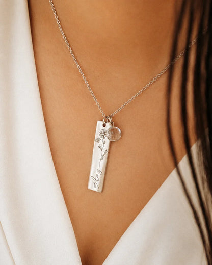 Model wearing a silver Eraya Jewel personalized birth flower, name, and birthstone pendant, featuring the engraved name Amy, an April daisy flower, and a clear quartz stone charm.