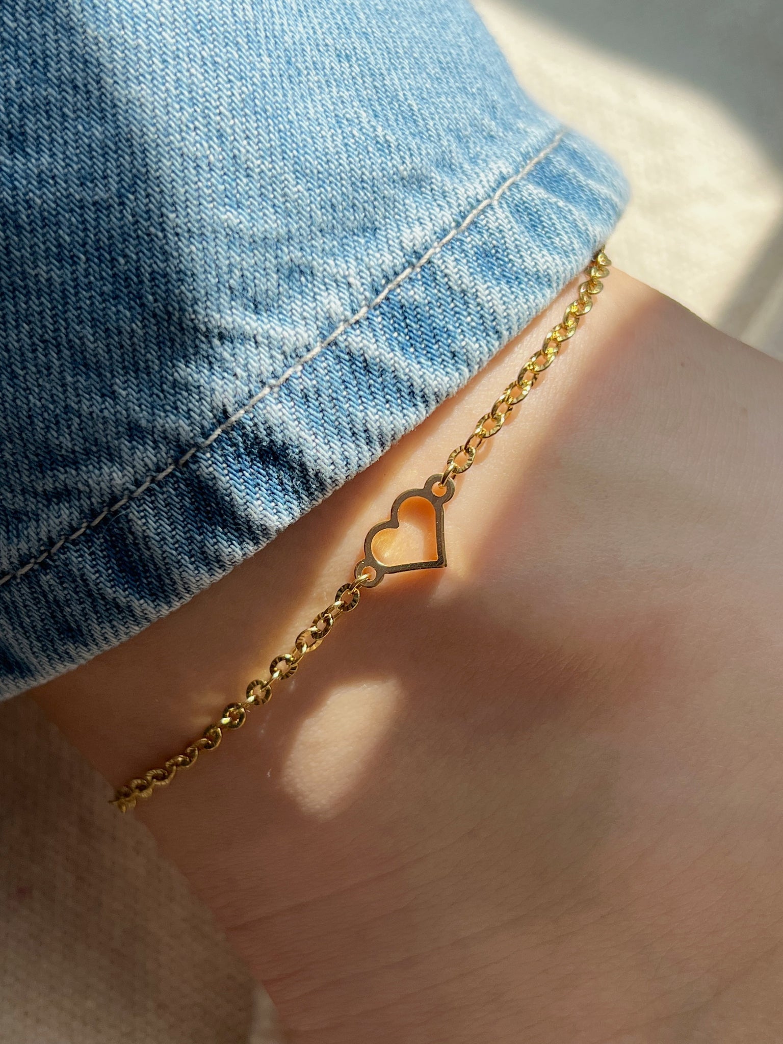 Minimalist gold heart anklet styled with casual denim jeans, perfect for everyday wear.