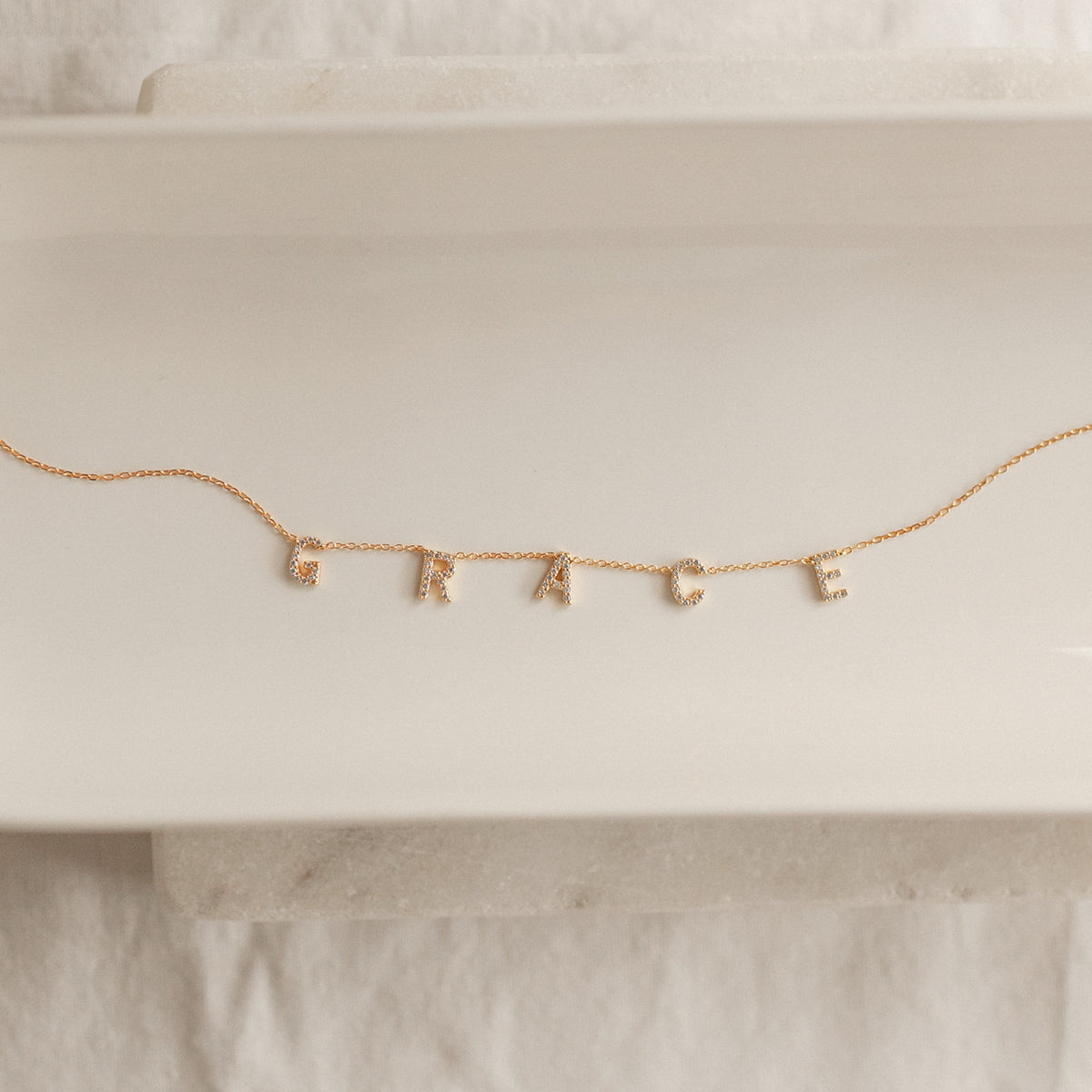 Woman wearing a Personalized Pavé Letter Name Necklace in 22K gold finish with custom name letters by Eraya Jewel.