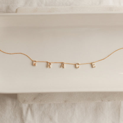 Woman wearing a Personalized Pavé Letter Name Necklace in 22K gold finish with custom name letters by Eraya Jewel.