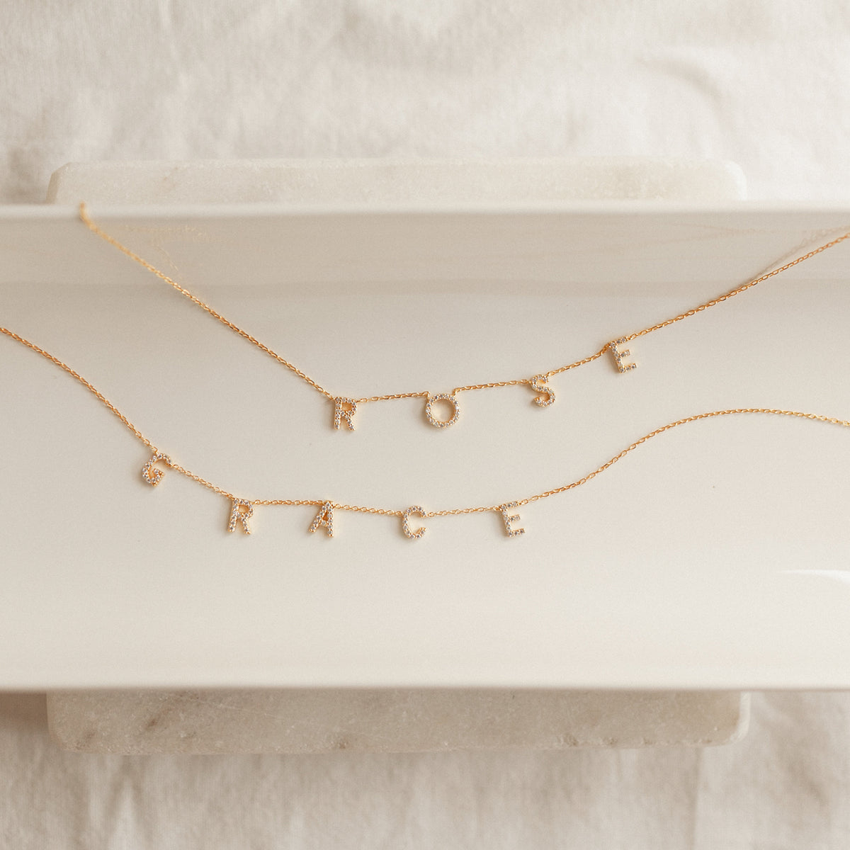 Flat lay of a custom Pavé Letter Name Necklace handcrafted with premium CZ letters for personalized everyday jewelry.