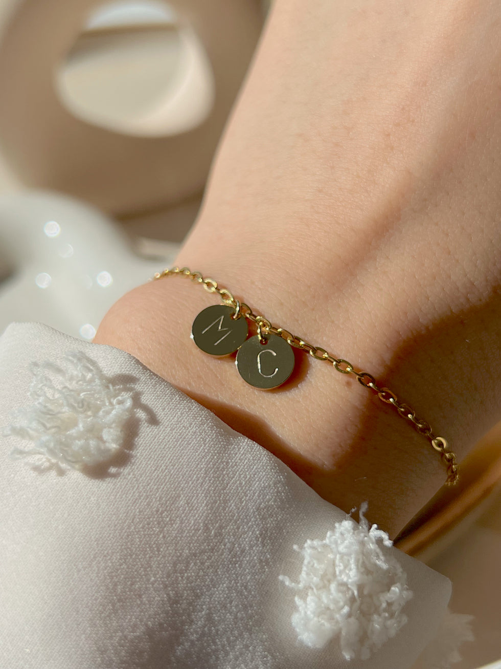 Women wearing his and her gold initial coin bracelet 