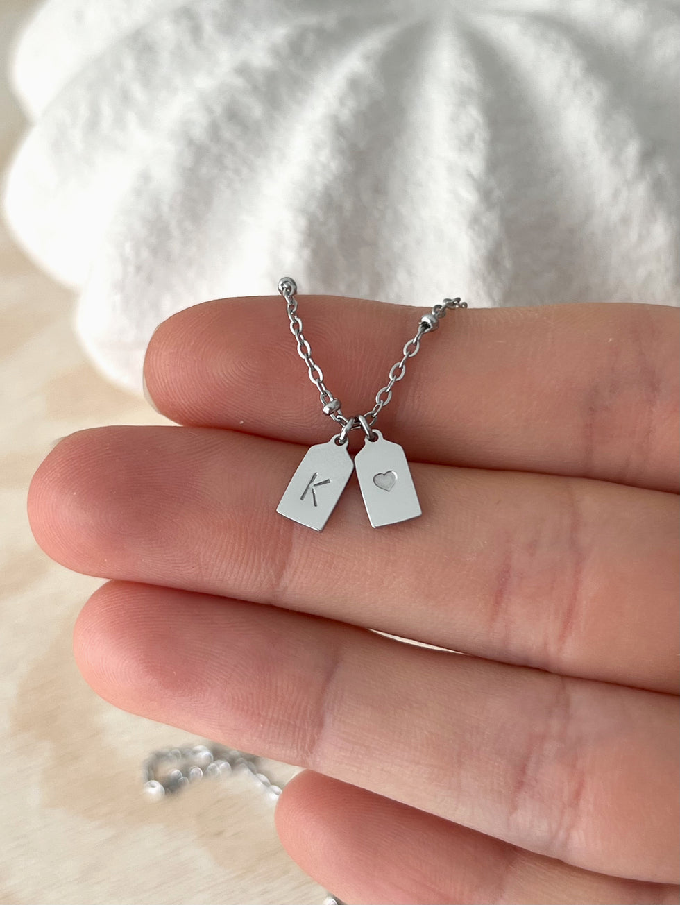 His and Her Initial Heart Pendant in silver polished finish on hand