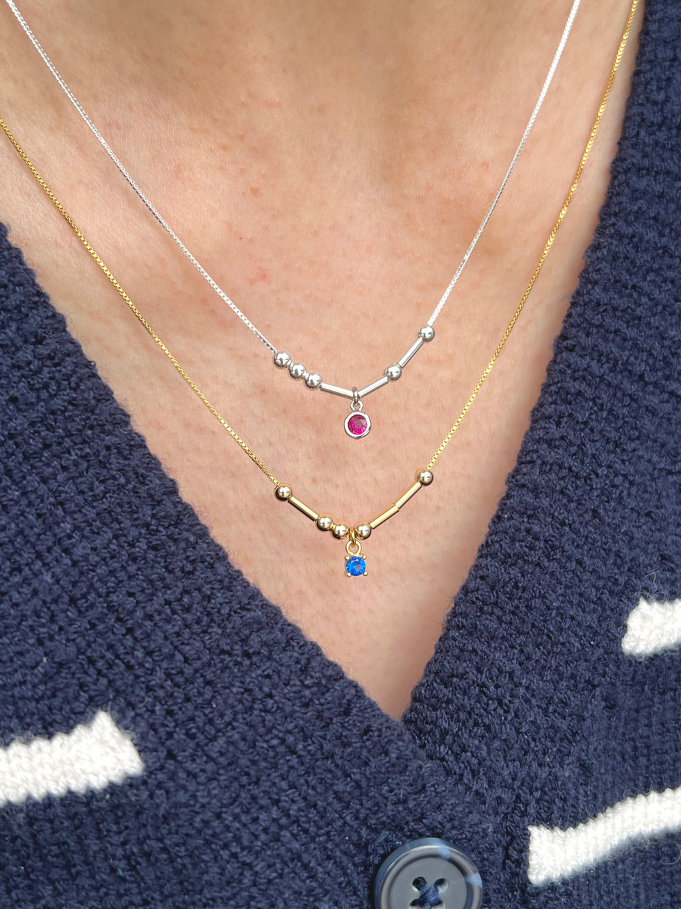 Model wearing gold and silver initial birthstone necklace 