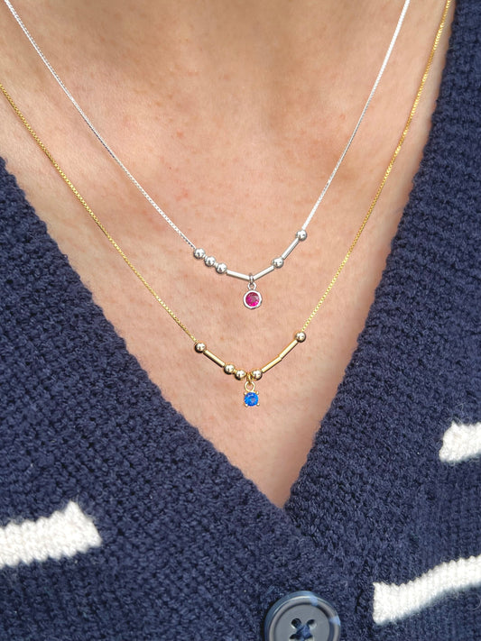 Model wearing gold and silver initial birthstone necklace 