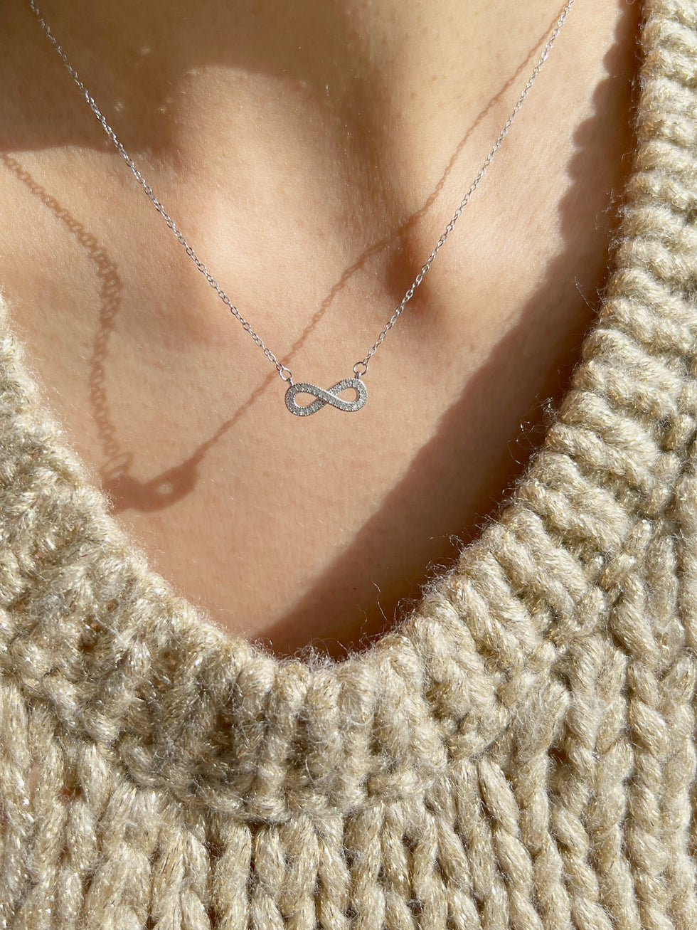 Close-up of silver infinity pendant necklaces on neck
