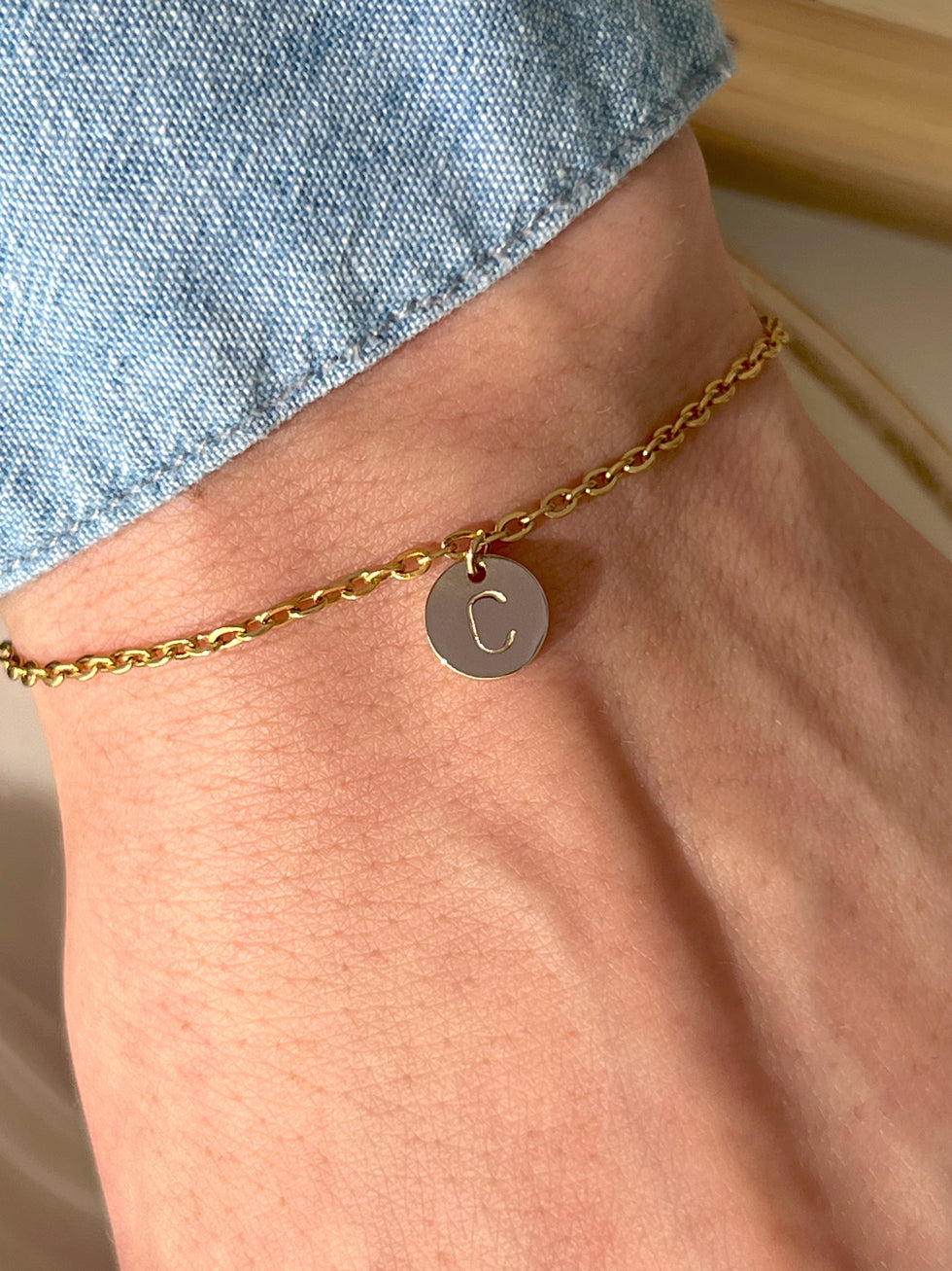 Man wearing her initial gold coin bracelet 