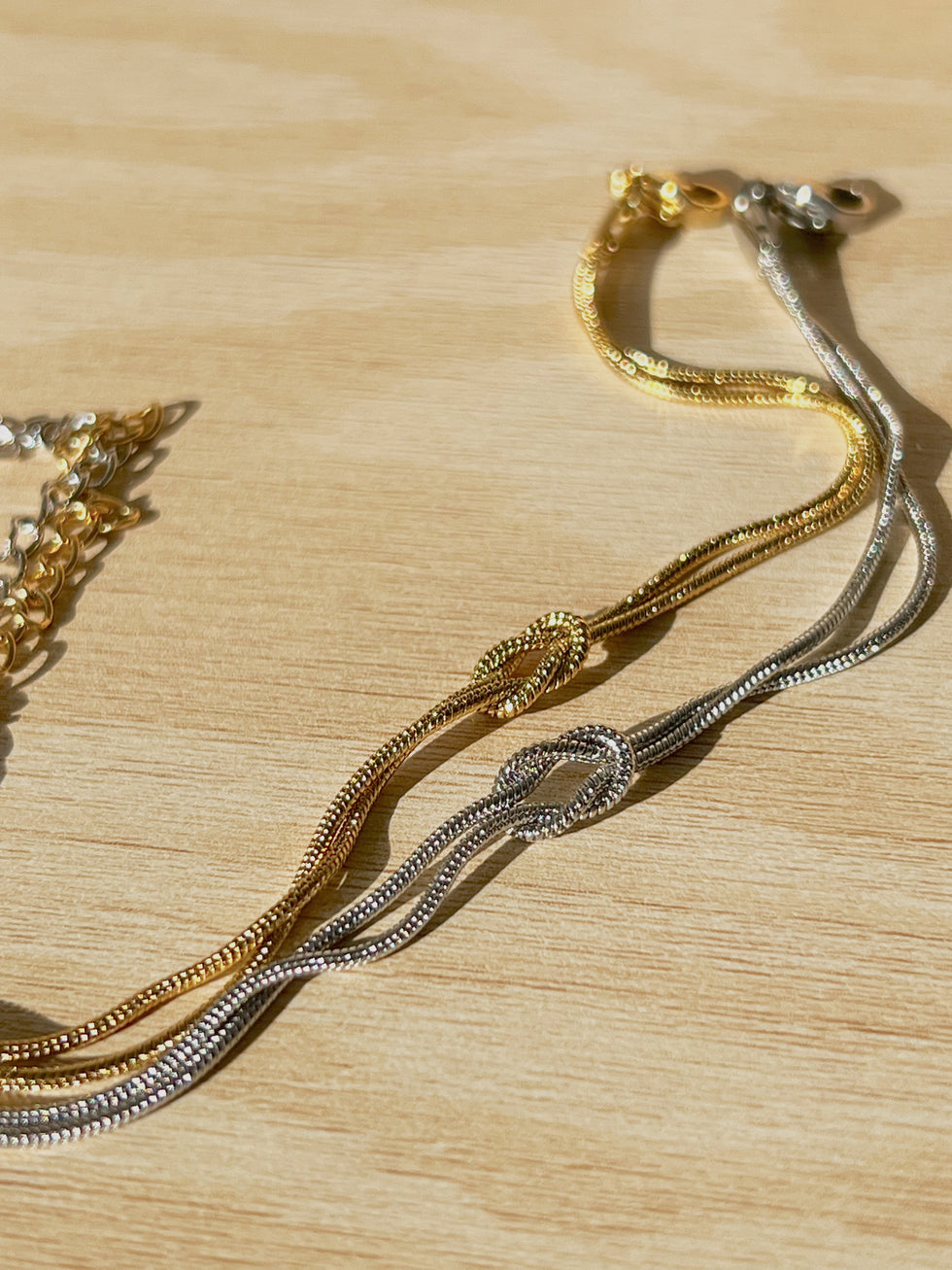 Gold and silver knot bracelets side by side, symbolizing unity and connection