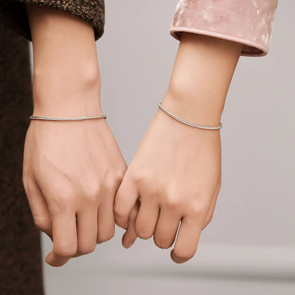 partners standing, both showing matching 925 silver bracelets