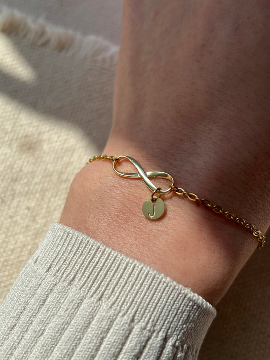 Model wearing gold infinity initial bracelet 