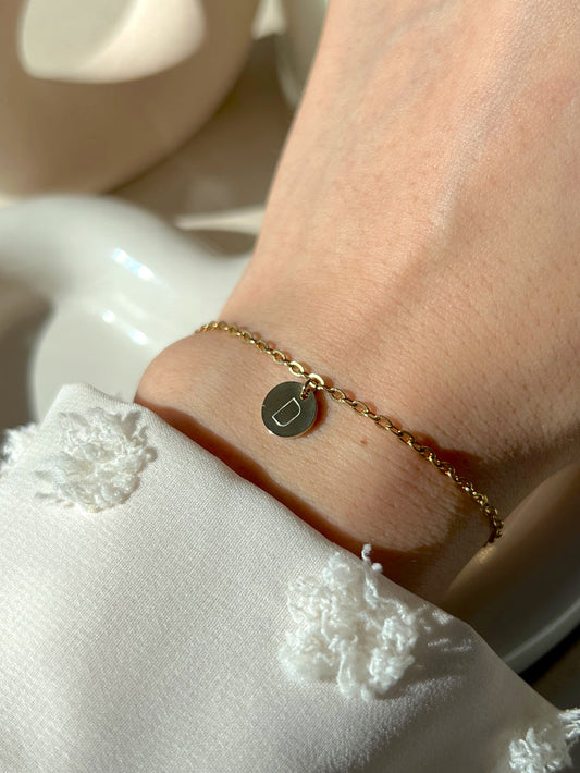 Model wearing gold initial coin bracelet 