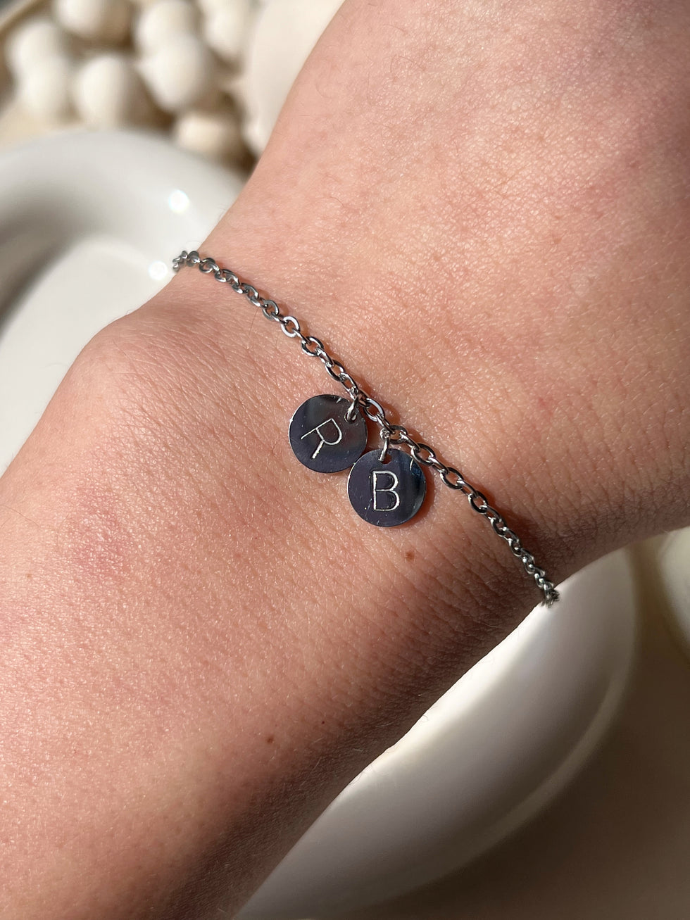 Model wearing silver his and her initial coin bracelet 