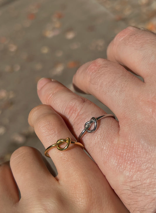Matching gold and silver knot rings on couple’s fingers, minimalist promise ring set for couples.