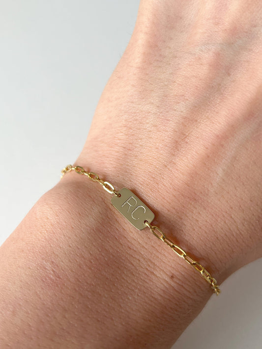Model wearing gold his and her initial bracelet 