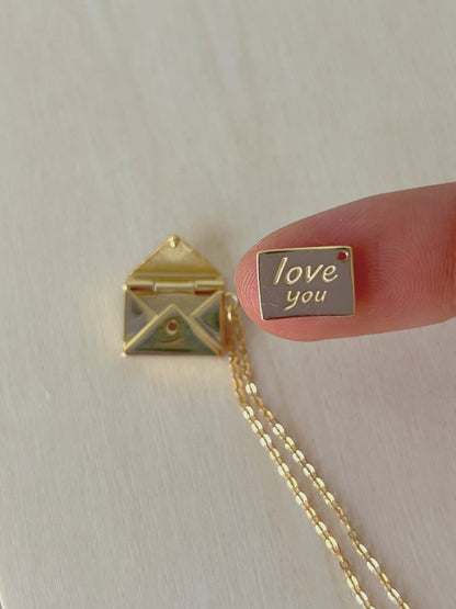Minimalist flatlay of envelope locket pendant with love note visible
