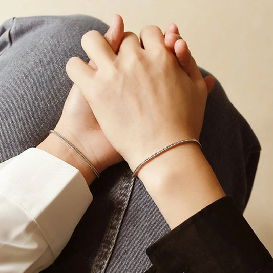 Couple sitting together holding hands wearing Forever Us bracelets
