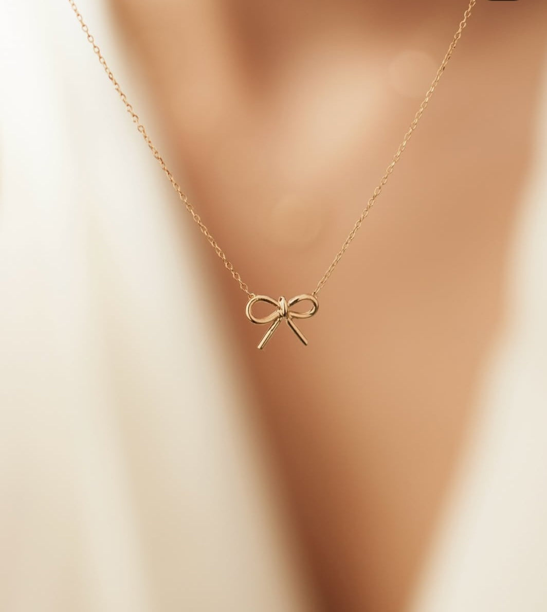 Close-up of dainty bow necklace on display for product shoot