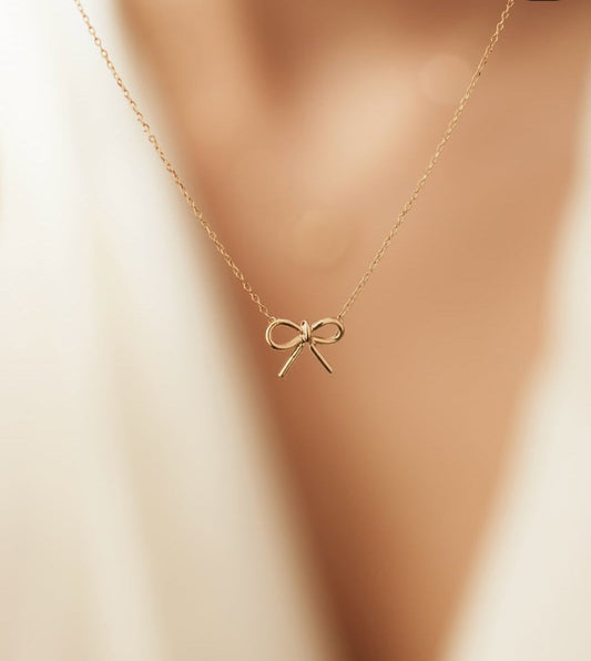 Close-up of dainty bow necklace on display for product shoot