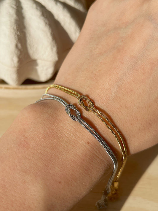 A model wearing both silver and gold knot bracelets styled with a casual outfit